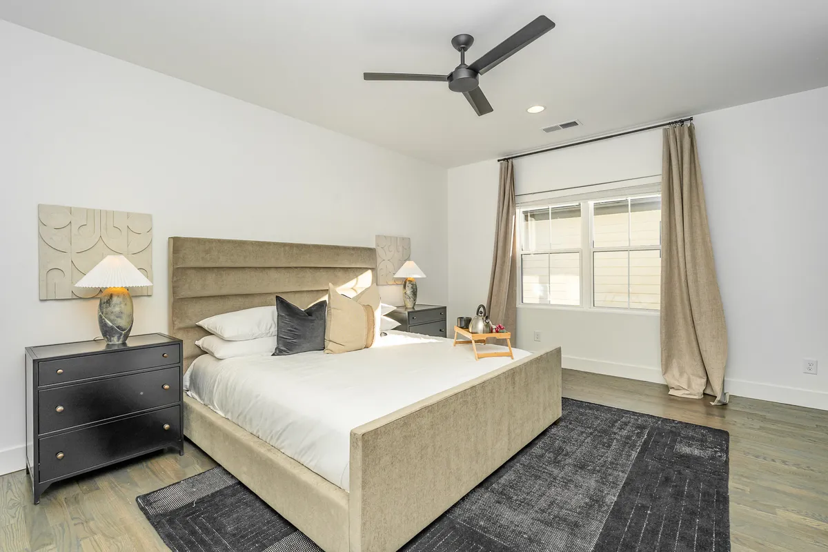 This image features a modern bedroom with a plush headboard, decorative pillows, and stylish nightstands with lamps. The muted tones and soft lighting create a soothing, serene atmosphere ideal for relaxation.