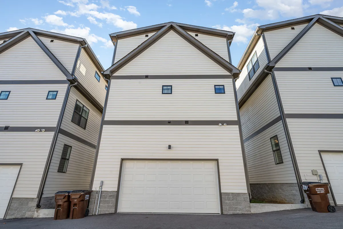 An exterior view focusing on the garage door and building facade, with windows visible above. The scene suggests easy vehicle access and secure, private parking immediately upon arrival.